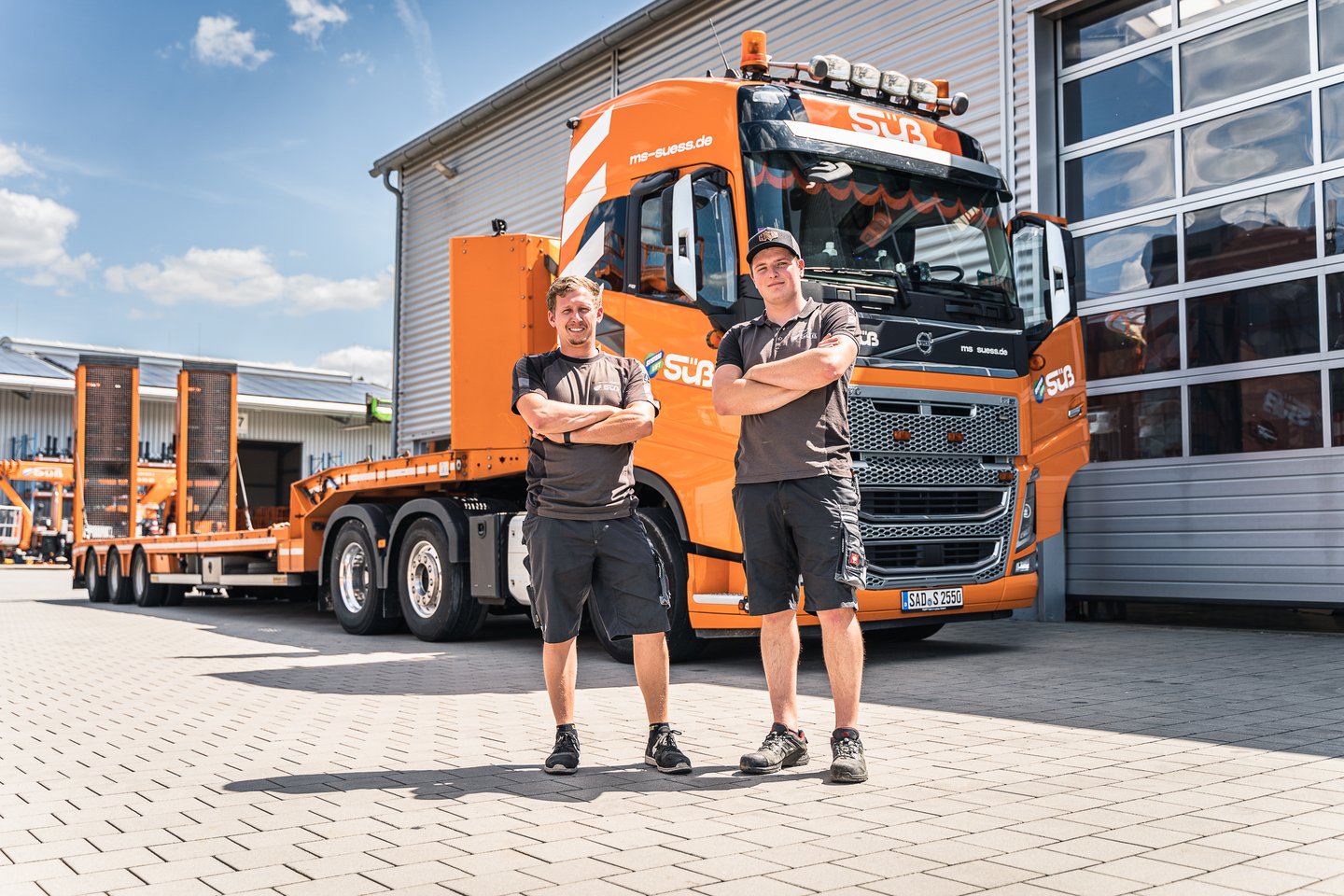 Süß-Mitarbeiter vor Volvo-LKW mit Tieflader